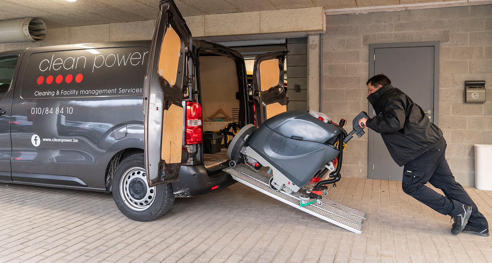 Vue latérale d’un handyman avec une machine laveuse dans un parking.