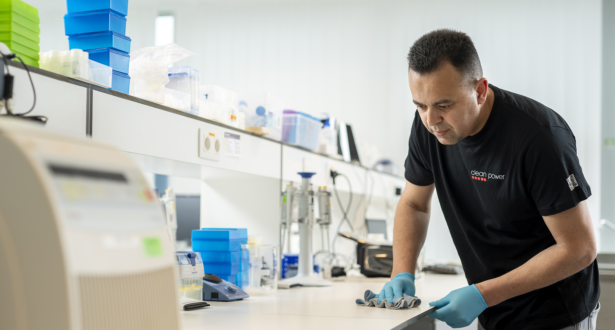 Homme utilisant un chiffon pour nettoyer un plan de travail dans un laboratoire.