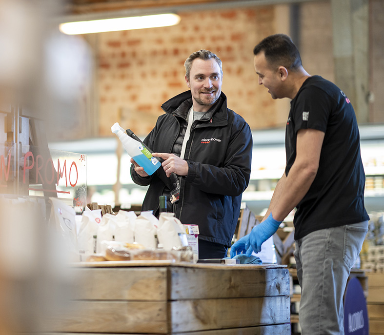 Manager indique le bon produit à utiliser pour un nettoyage responsable dans un magasin.
