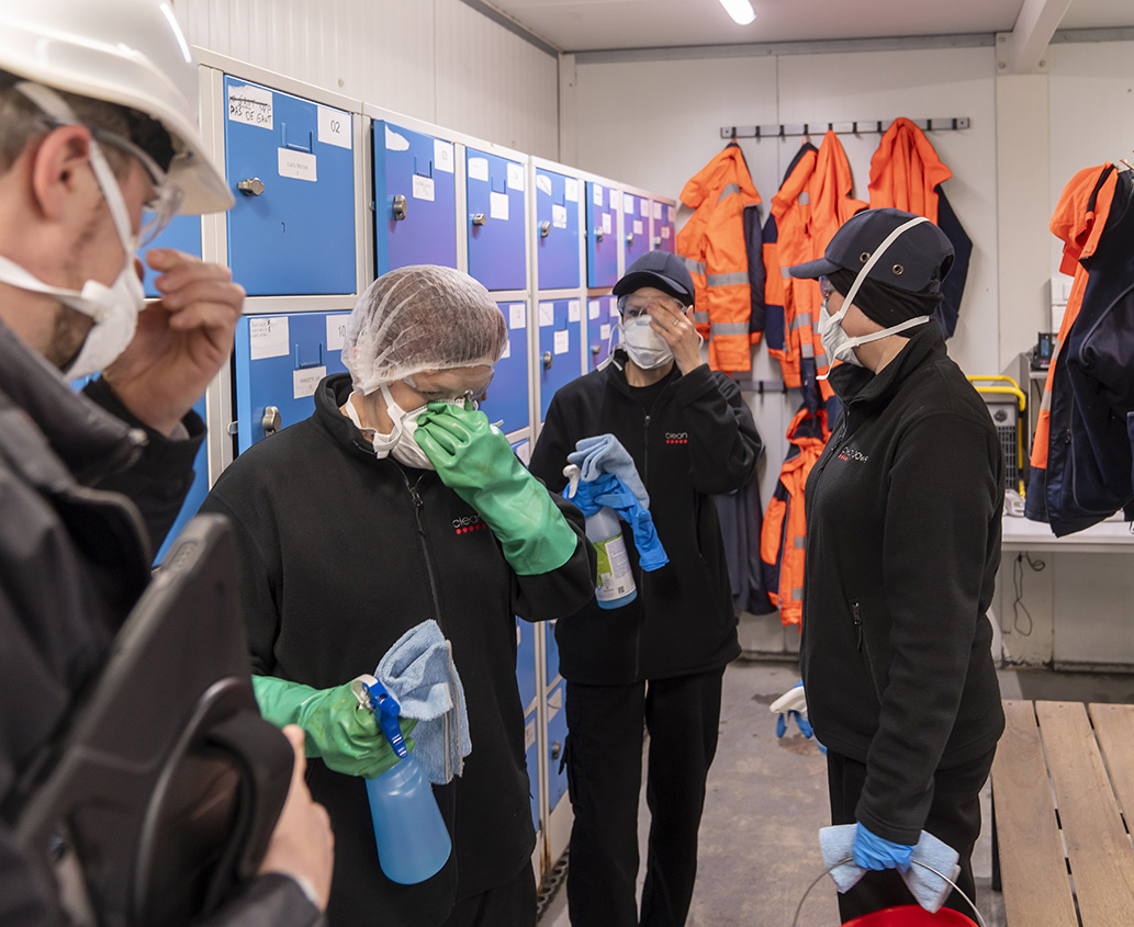 Techniciens de nettoyage d’une usine en train de s'équiper d’un masque de protection.