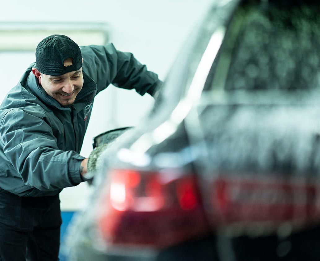 Prestation d’un professionnel qui nettoie une voiture avec du savon.