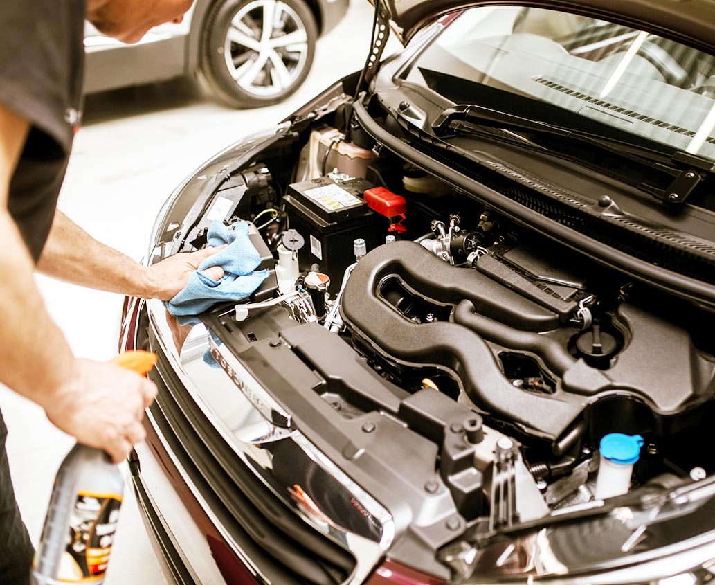 Nettoyage du moteur d’une voiture dans un garage.