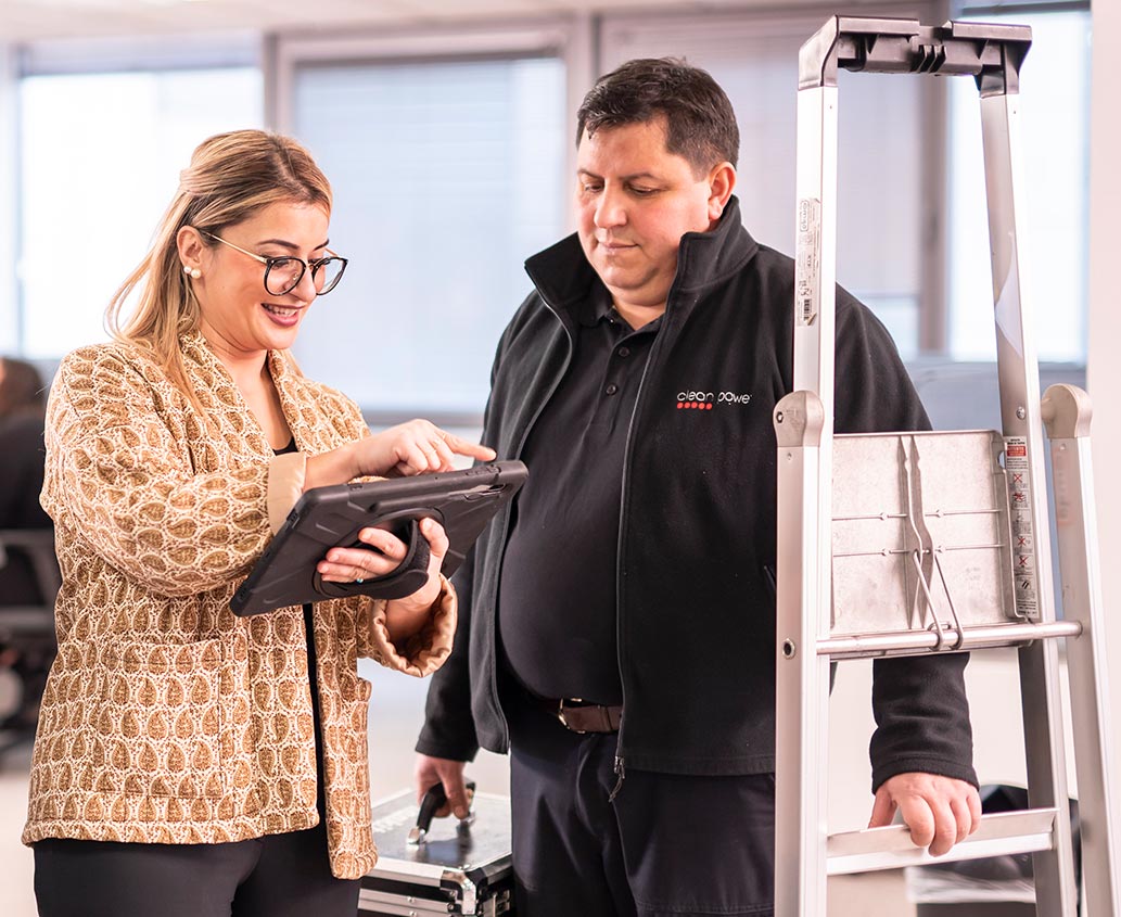 Femme souriante indiquant des consignes sur une tablette à un handyman.