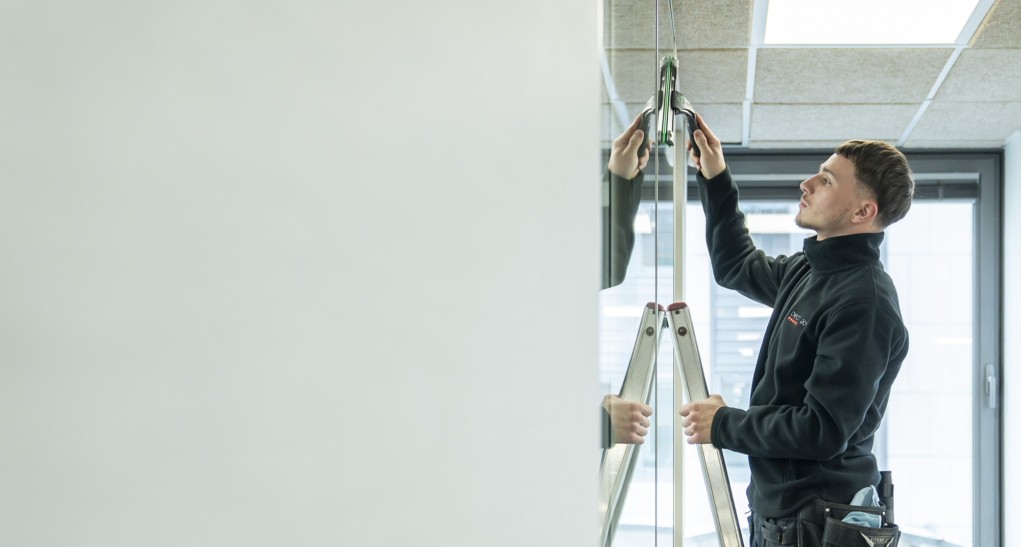 Professionnel qui nettoie une vitre dans un bureau.