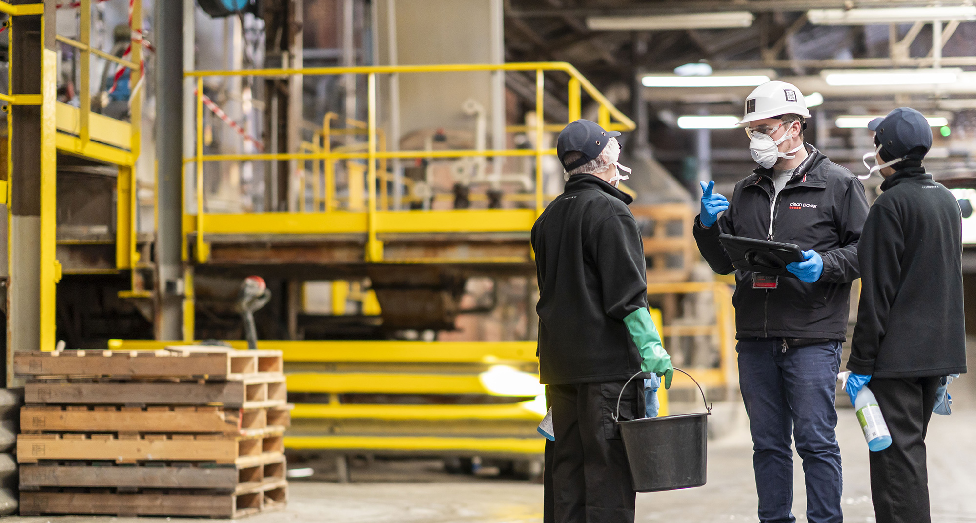 Professionnels du nettoyage industriel écoutent les consignes d’un manager dans une usine.