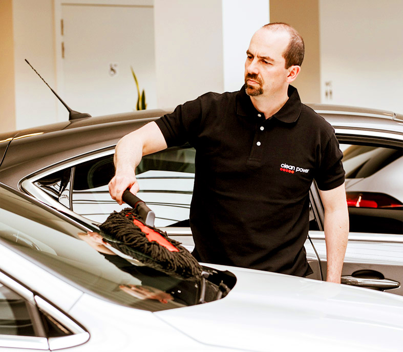 Homme nettoie une voiture dans un garage.
