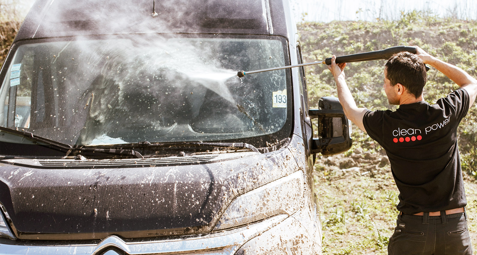 Membre du personnel vaporisant de l’eau pour nettoyer le pare-brise d’une camionette.
