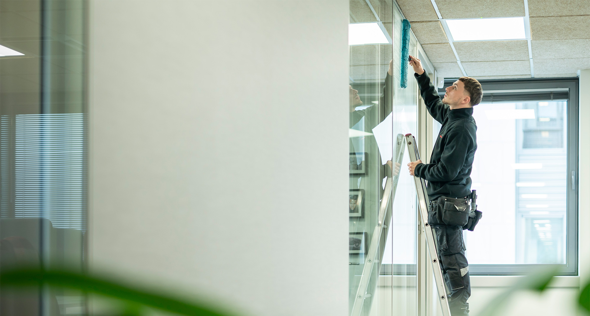 Vue latérale d’un membre du personnel qui lave les vitres d’un bureau.